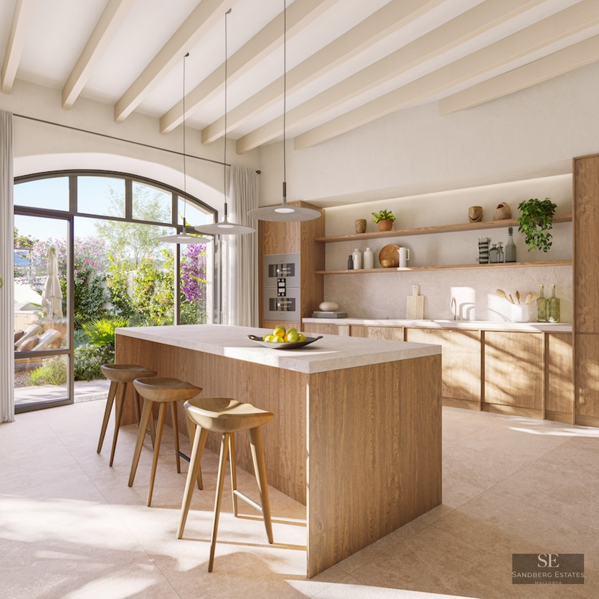 Bright kitchen with a large wooden island, three stools, and an arched glass door looking out to a lush green garden.