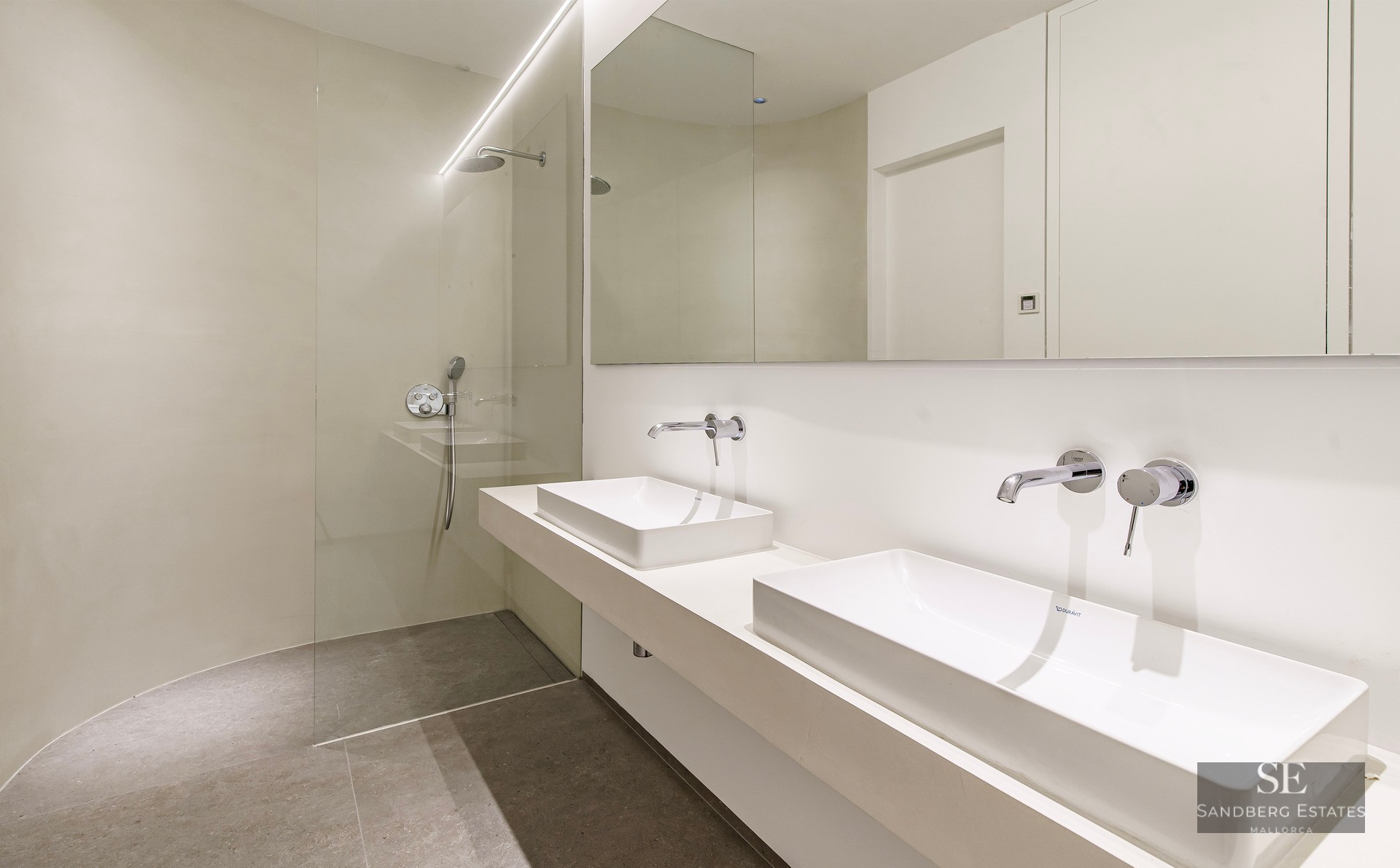 Modern bathroom featuring two white vessel sinks, wall-mounted chrome faucets, and a glass-enclosed walk-in shower.
