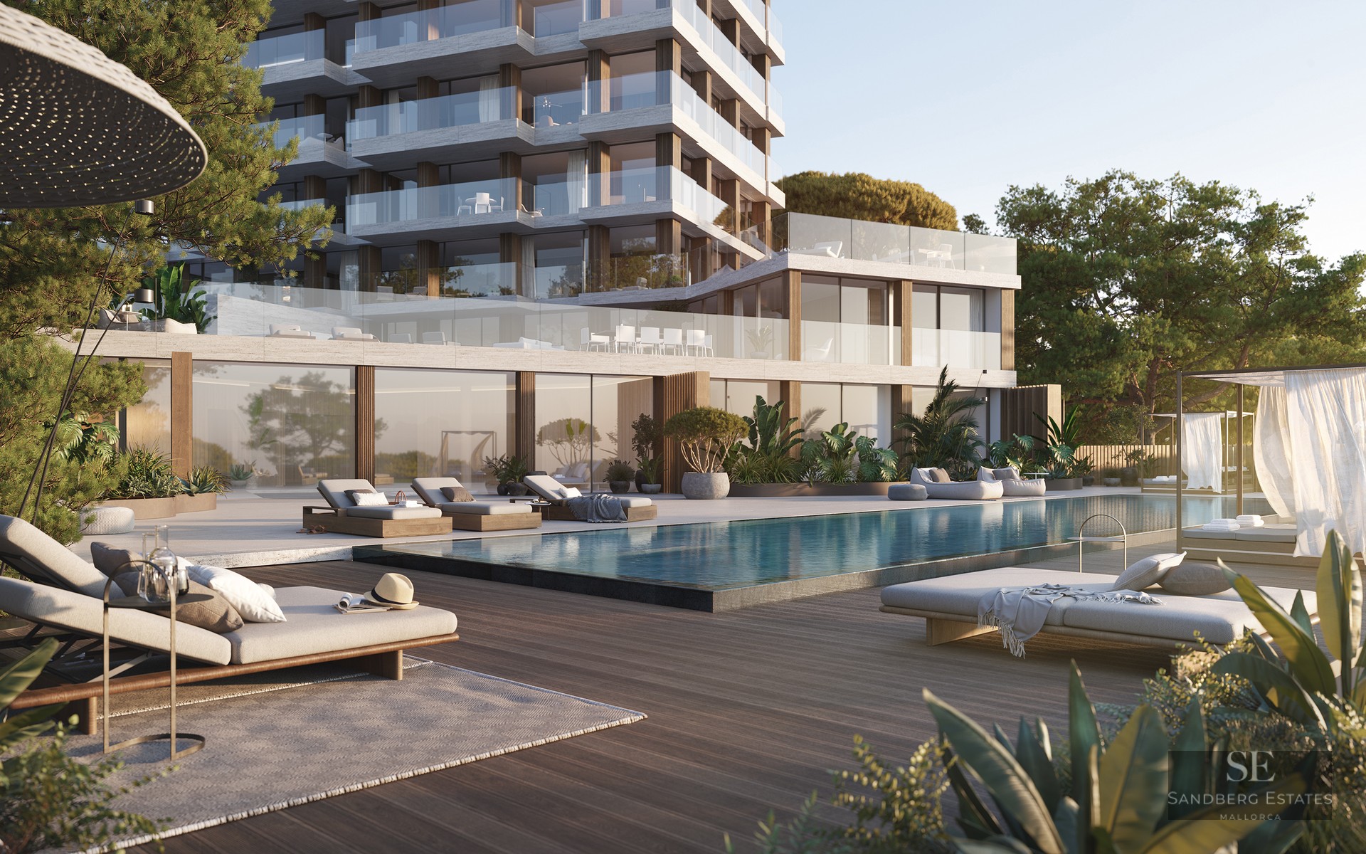 Modern apartment building with a large swimming pool, wooden deck, luxury lounge chairs, and lush green gardens.
