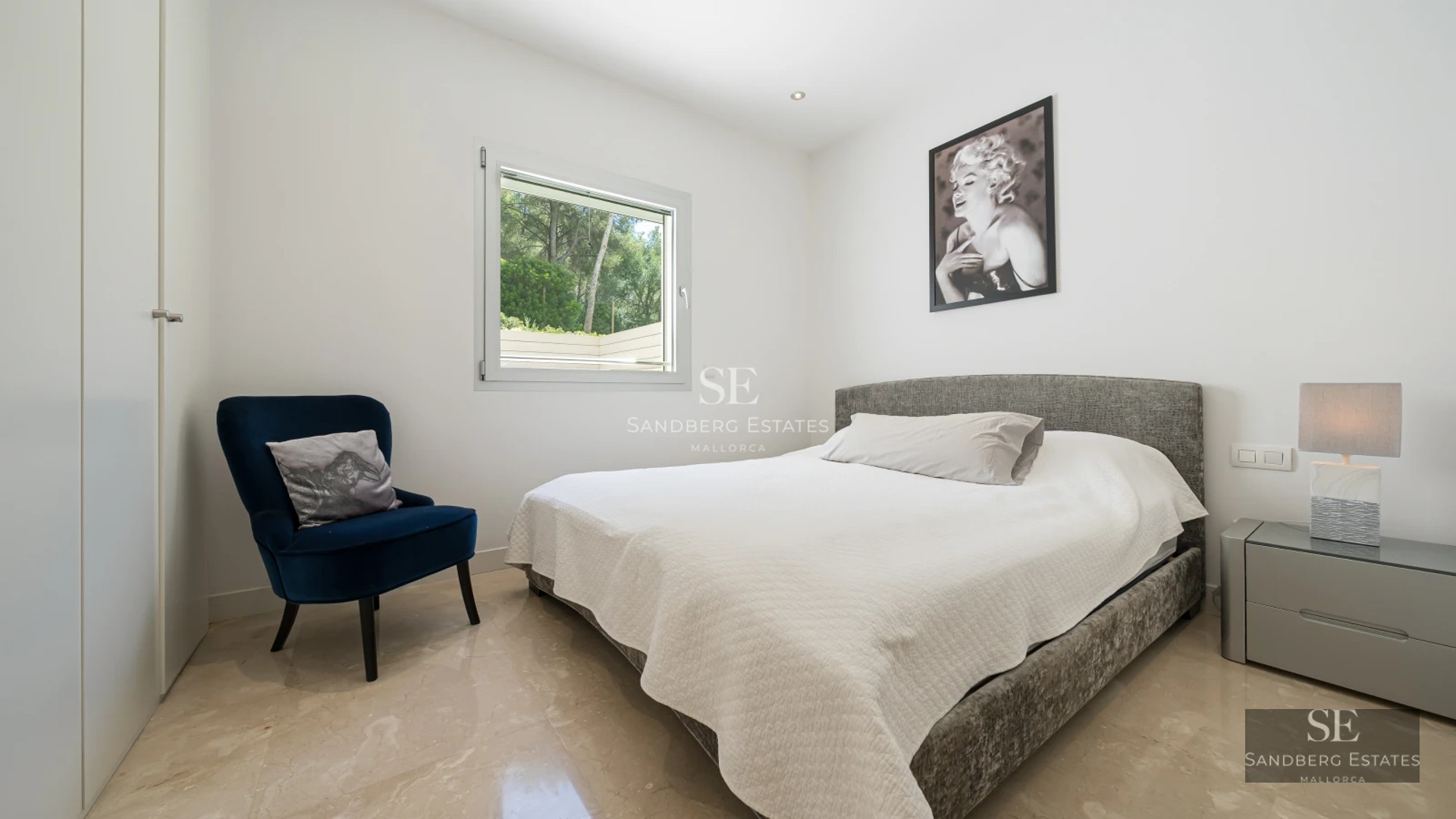 Bright living room with balcony, sea view, and modern furniture. Wooden floors, white walls, and minimalist decor.