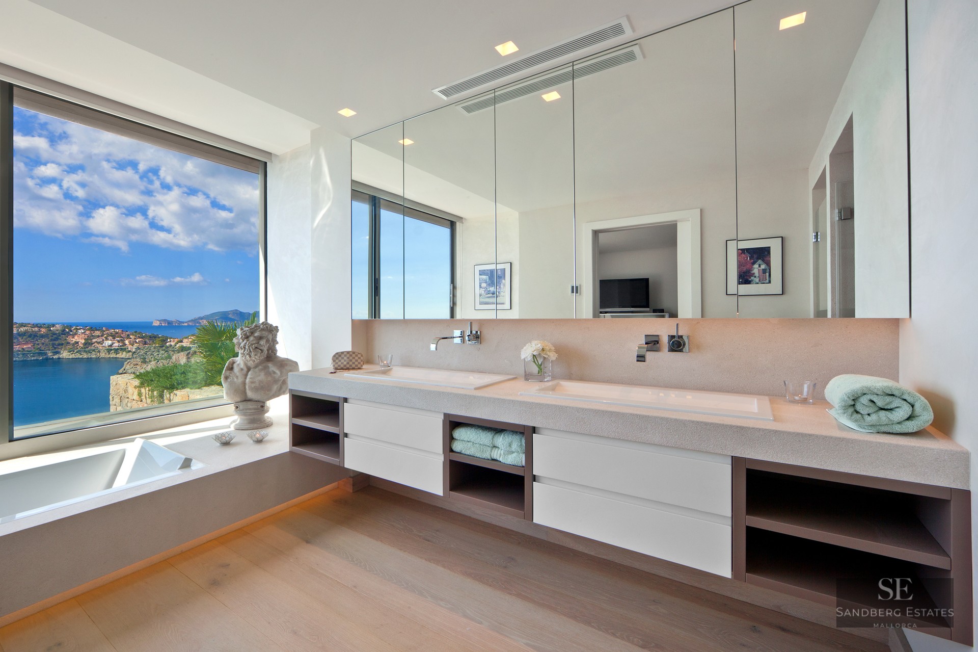 Modern master bathroom featuring a double vanity and a floor-to-ceiling window overlooking the sea.