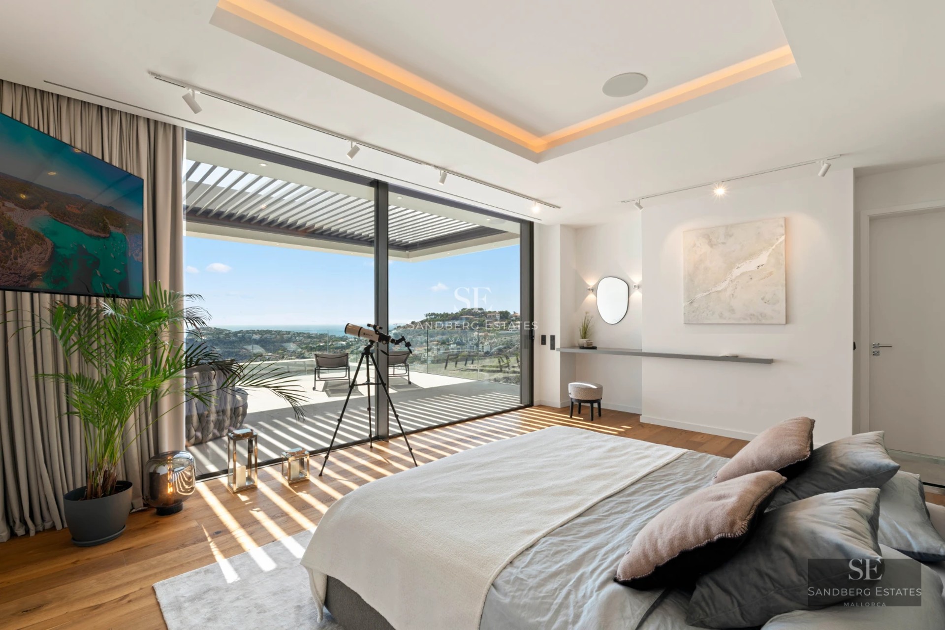 View of a turquoise pool surrounded by greenery and a modern house with large windows reflecting the blue sky.