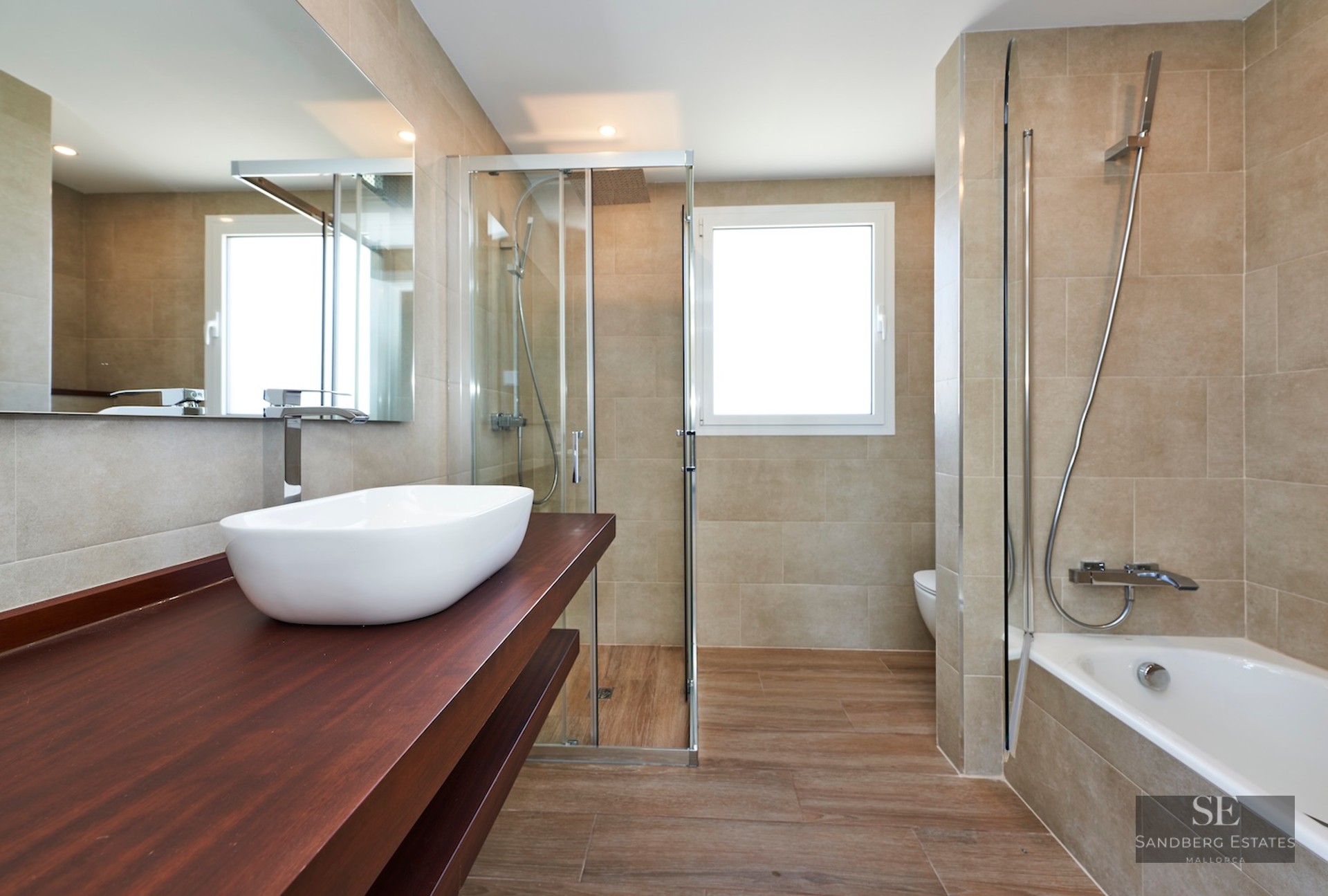 Modern bathroom featuring a white vessel sink on a wood vanity, a glass shower, and a built-in bathtub.