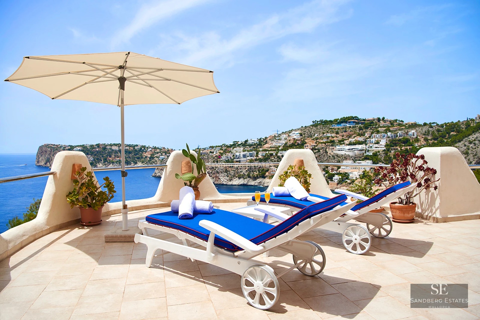 Spacious terrace with pool, sun loungers, and panoramic sea views. Modern design with glass railing and wooden flooring.