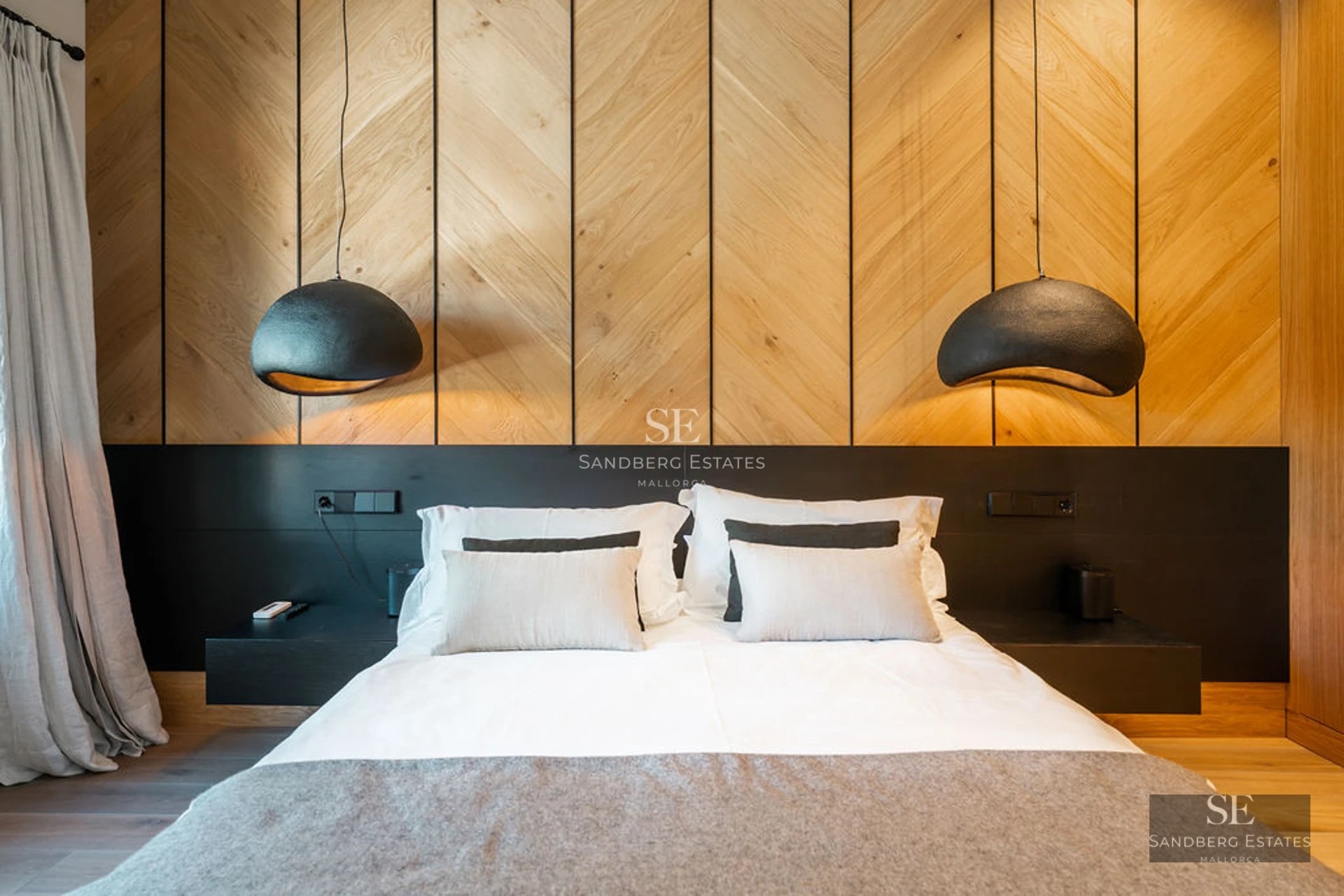 View of infinity pool with stone edge, sun loungers and lush vegetation. Modern and elegant design with clear blue sky.