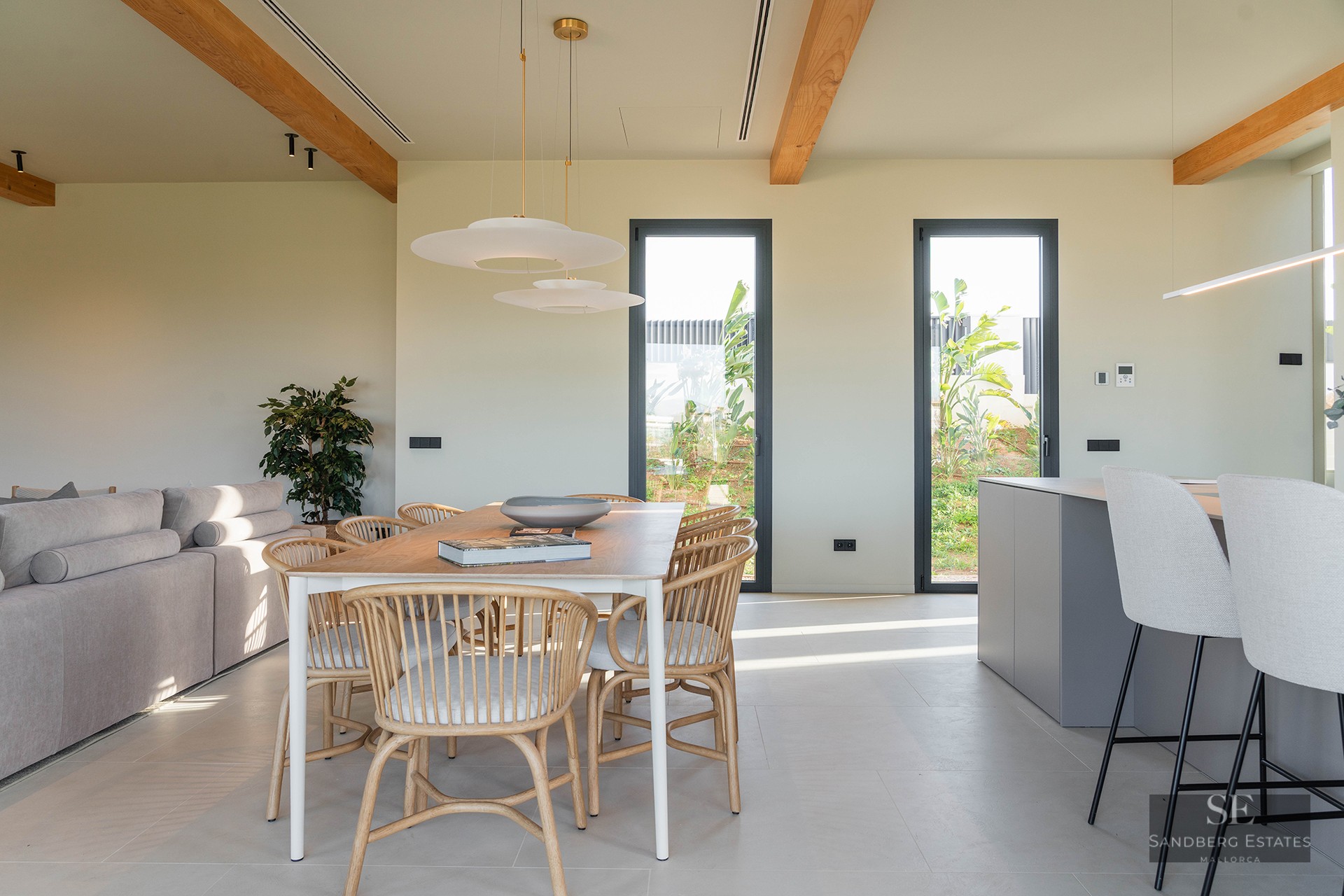 Bright dining room featuring a wooden table, designer chairs, and exposed wooden ceiling beams.