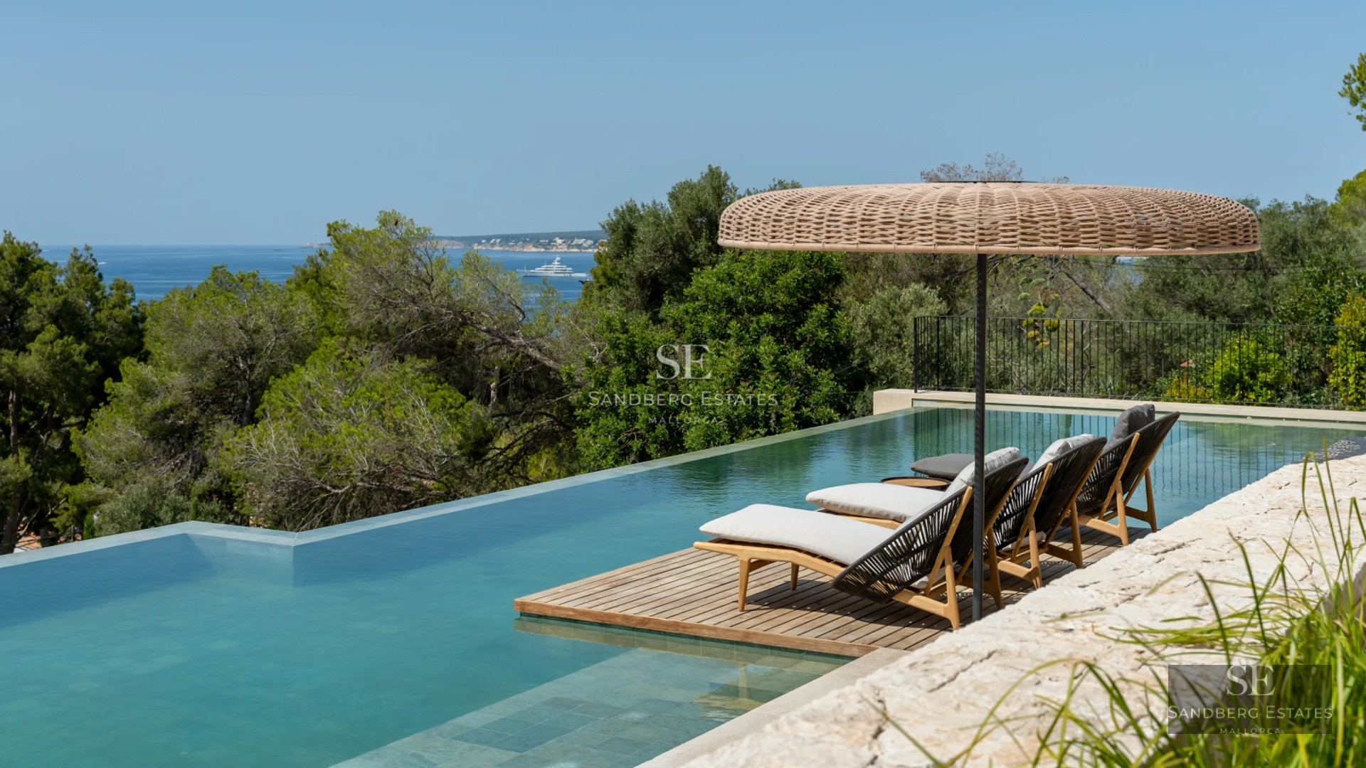 Exterior view of a modern villa featuring an infinity pool, expansive terraces, lush greenery, and minimalist architecture.