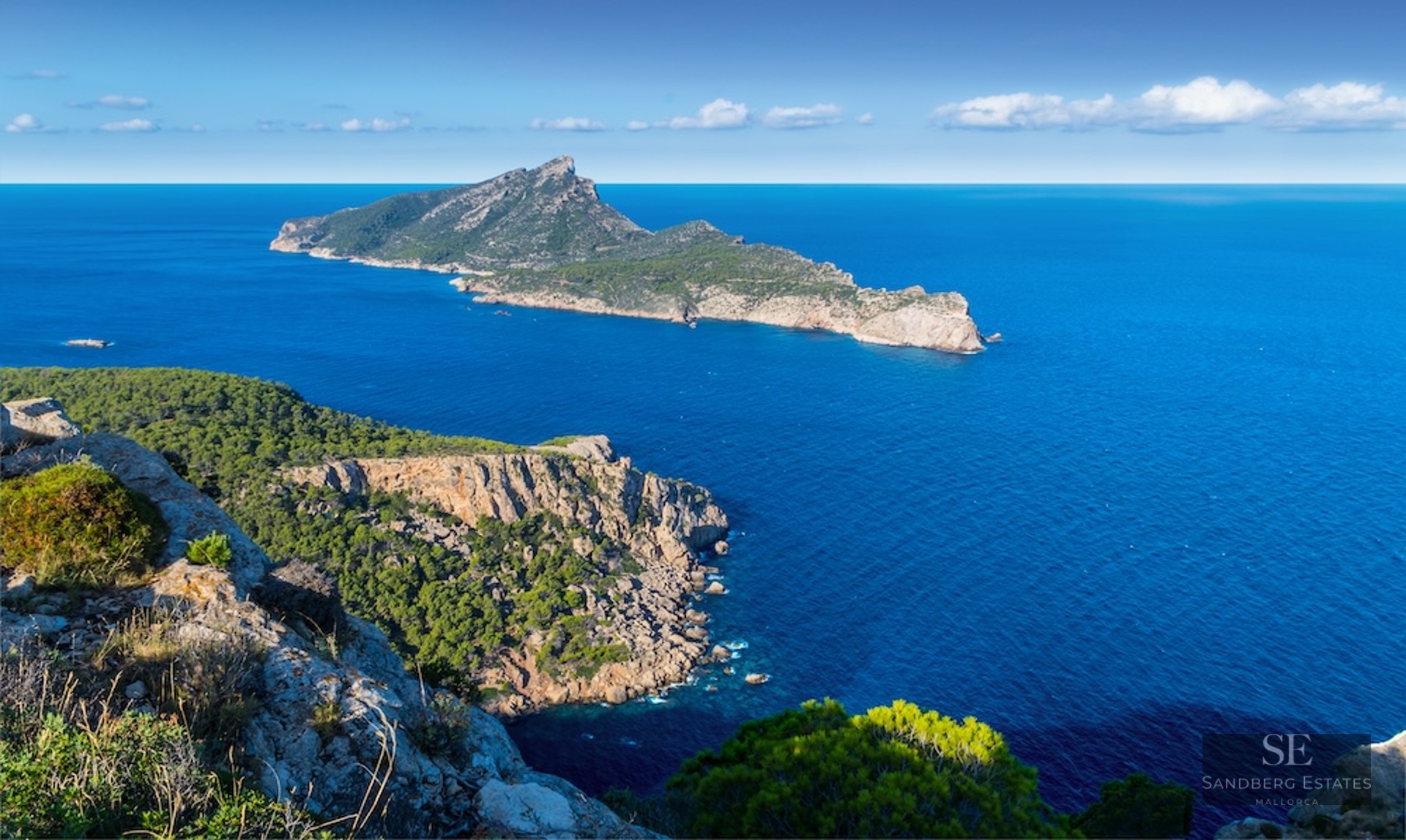 Elevated view of Mallorca's rocky coastline with Dragonera Island set against the deep blue Mediterranean Sea.
