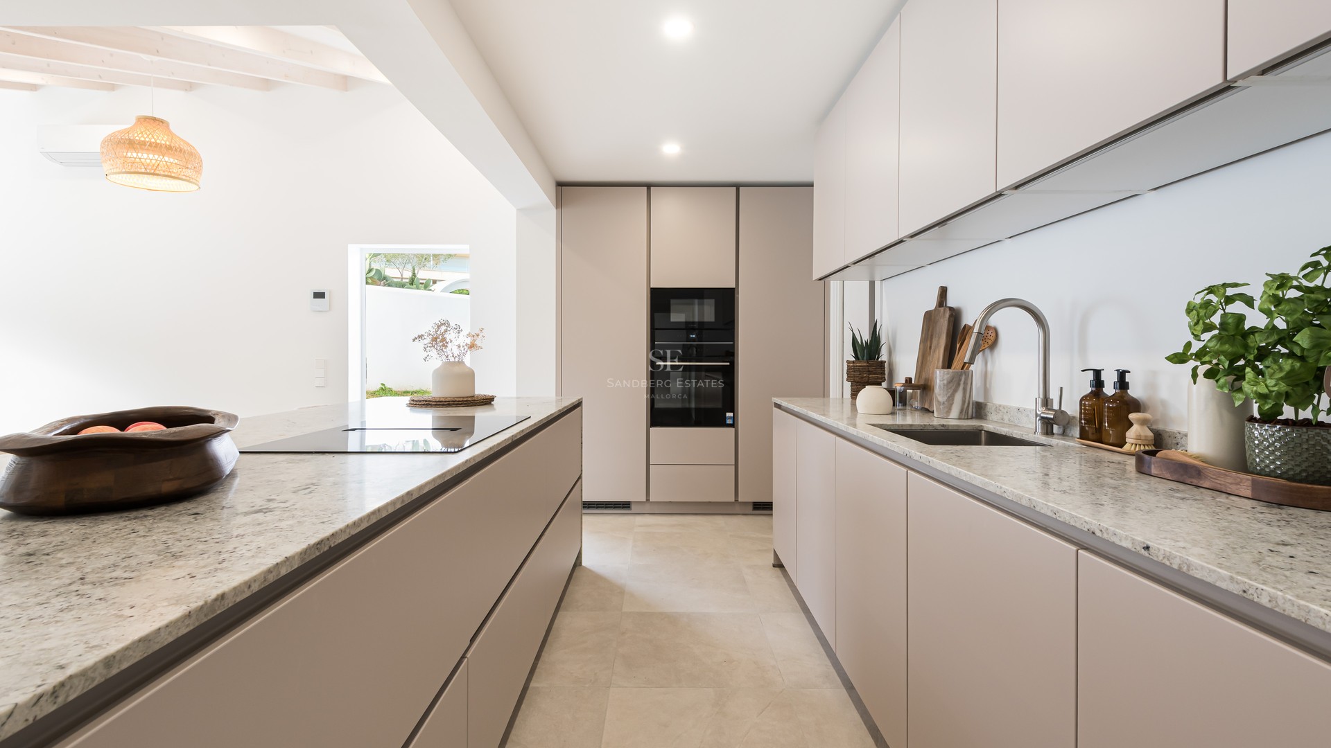 Cuisine contemporaine beige avec plans de travail en granit, îlot central et appareils électroménagers intégrés.