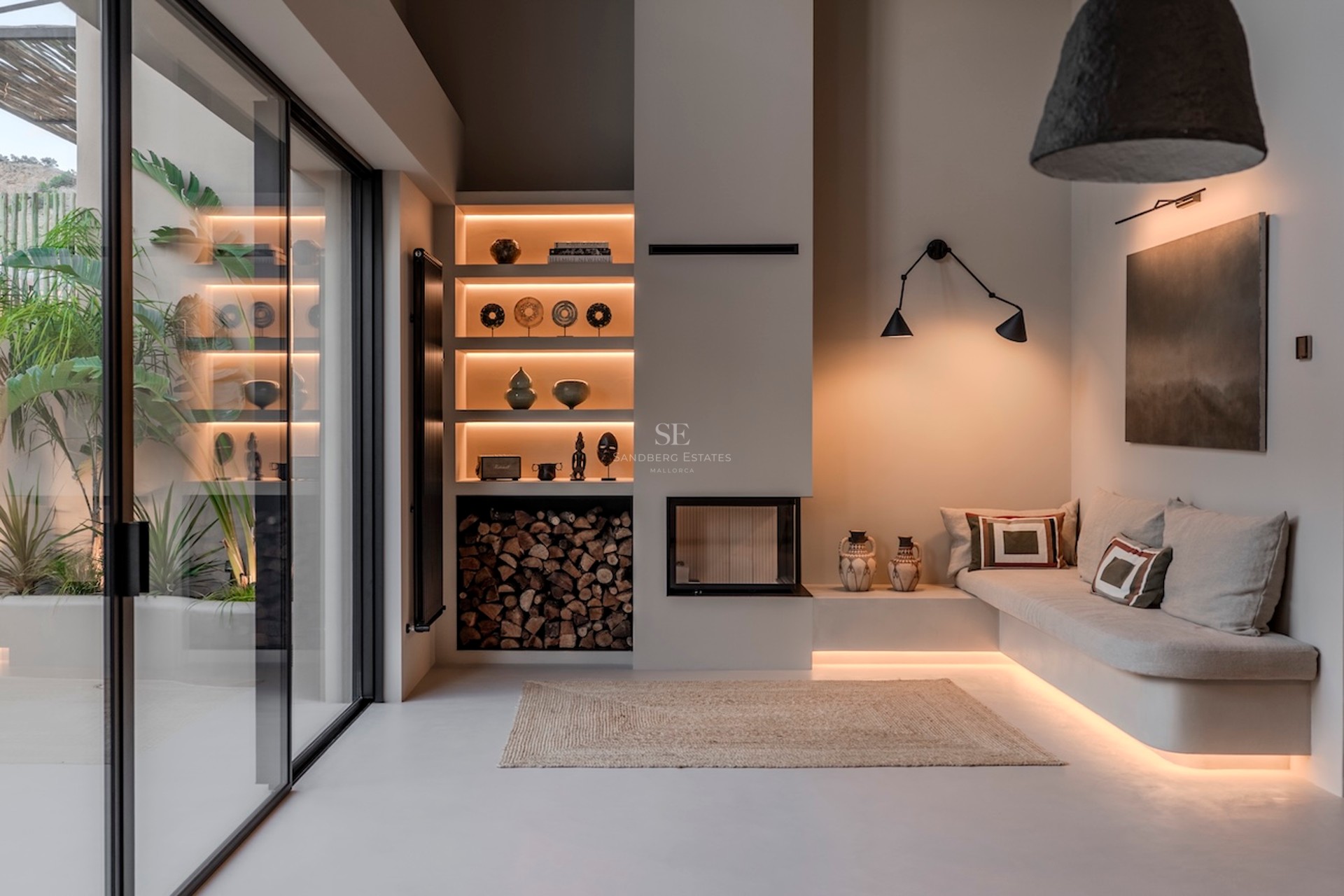 Salon minimaliste moderne avec canapé intégré, éclairage encastré, cheminée et grandes baies vitrées coulissantes.