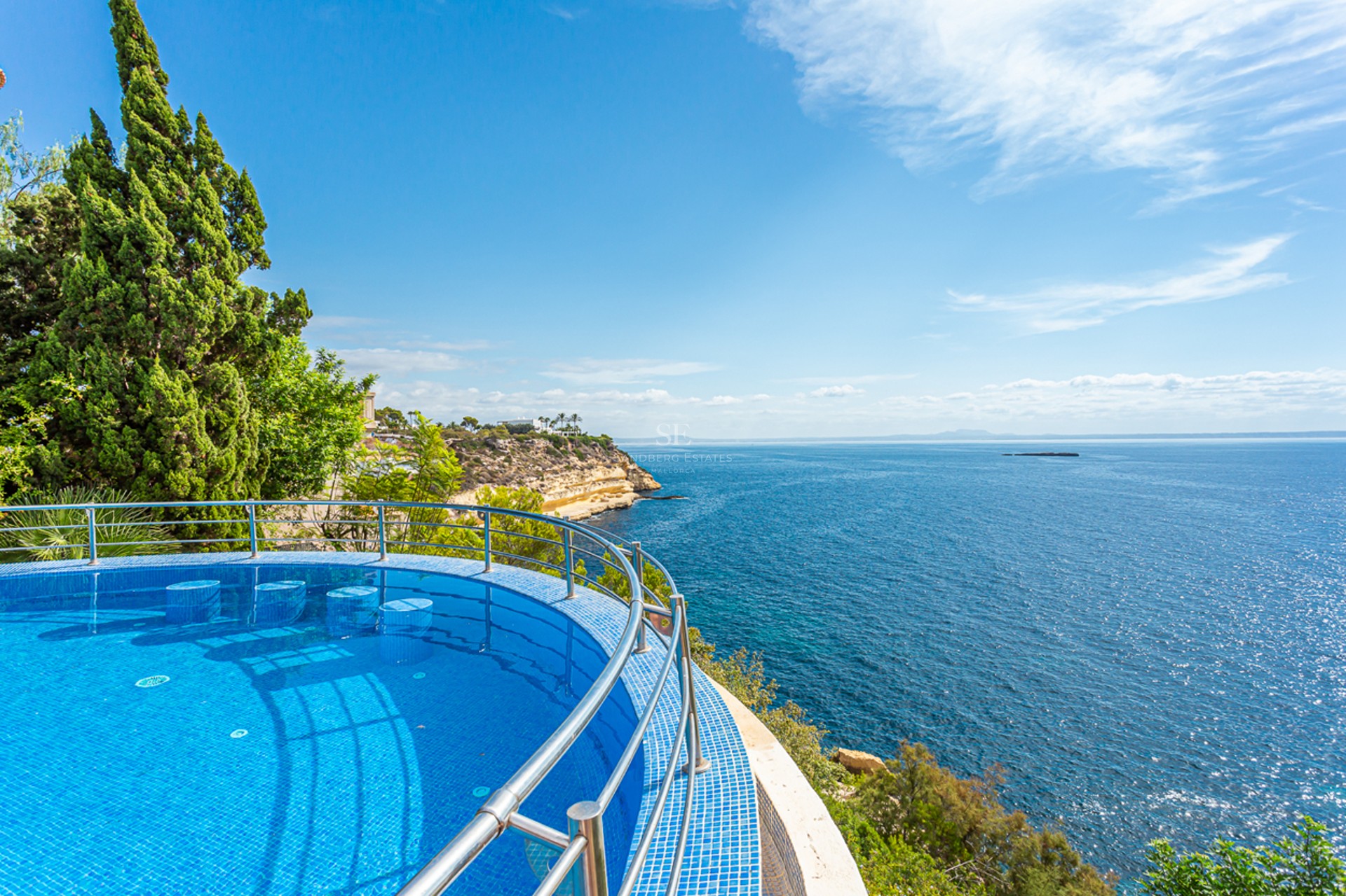 Grand balcon avec vue sur la mer, mobilier moderne, garde-corps en verre. Espace lumineux et élégant. Détails architecturaux design.