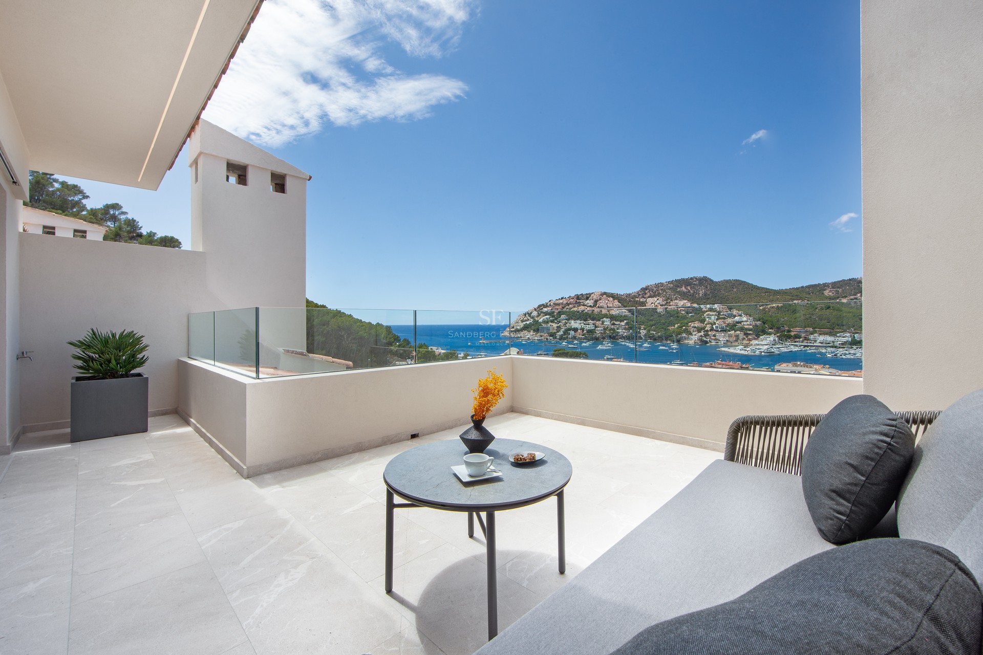 Terrasse de luxe avec garde-corps en verre, canapé extérieur et vue imprenable sur un port méditerranéen.