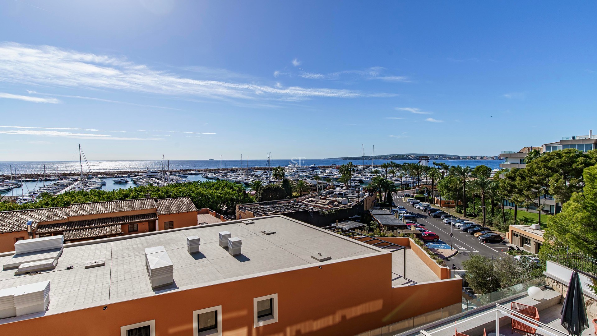Elevated view overlooking a marina with yachts and the Mediterranean sea under a clear blue sky.
