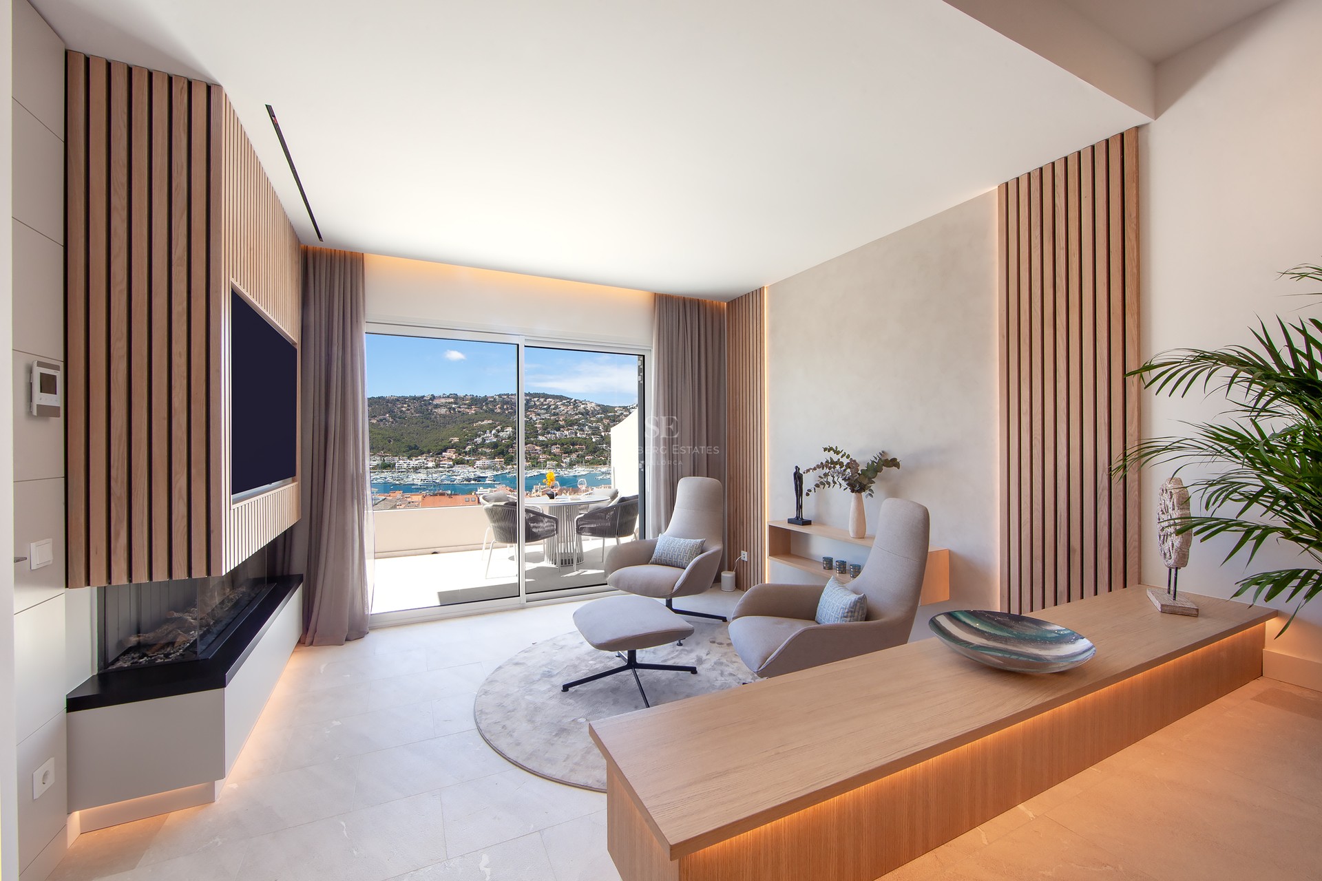 Salon moderne avec lattes de bois, fauteuils design et vue panoramique sur le port à travers des baies vitrées.