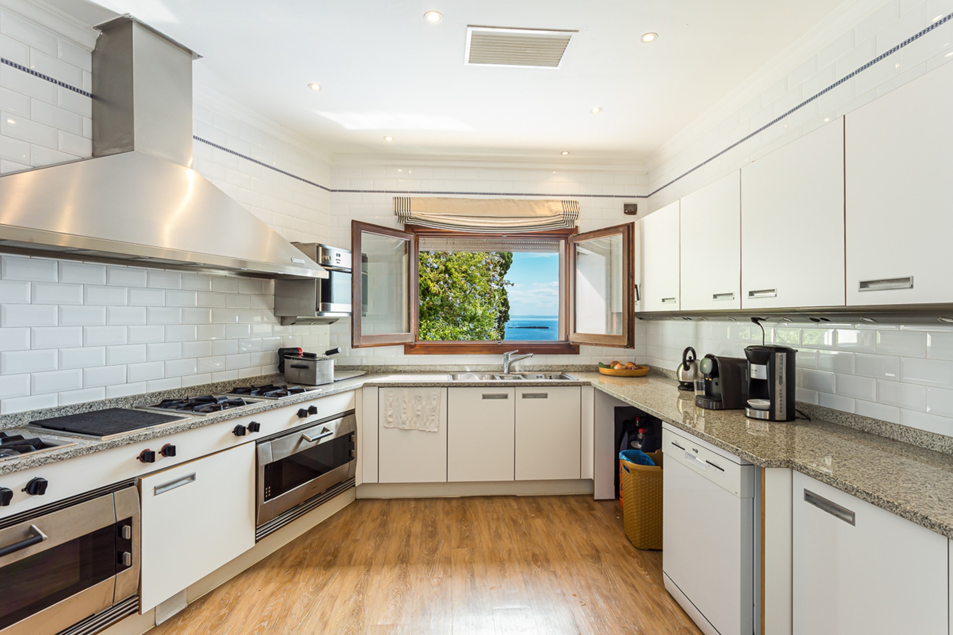 Extérieur d'une villa moderne avec piscine à débordement, grandes terrasses, design minimaliste et vues panoramiques. Façade blanche et végétation luxuriante.