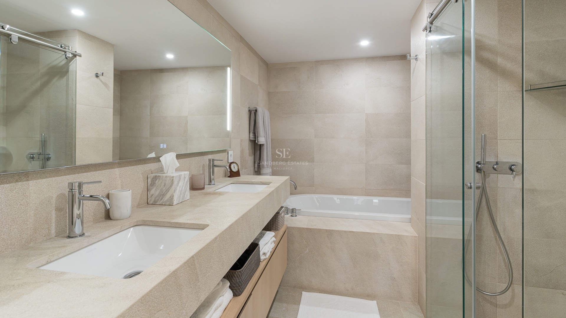 Modern bathroom featuring a double vanity with integrated stone sinks, a bathtub, and a glass-enclosed shower.