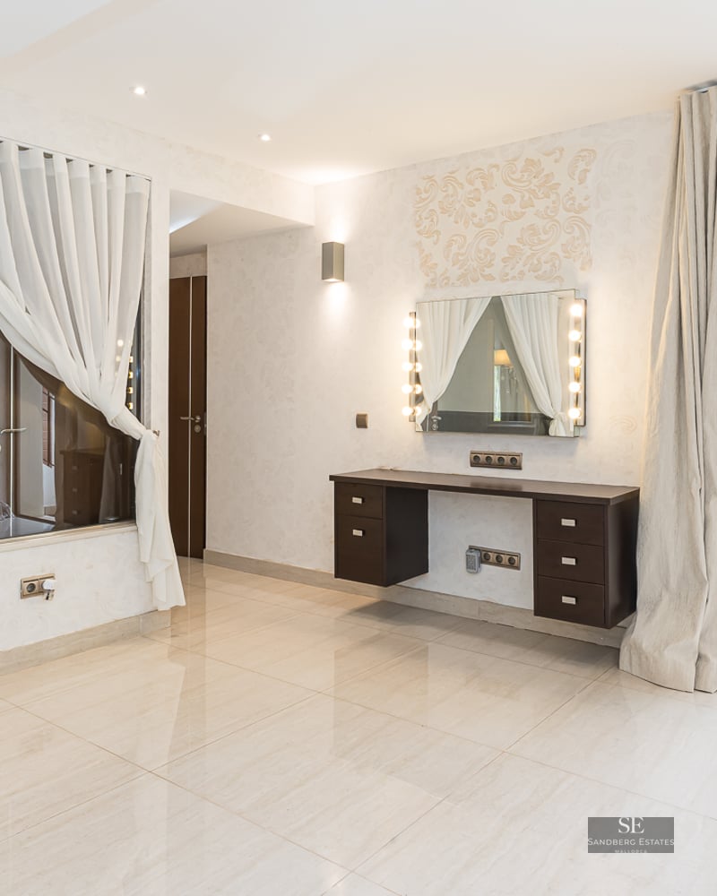 Bright dressing area with a Hollywood mirror vanity, glass wall to a bathroom, and sliding doors to a forest-view terrace.
