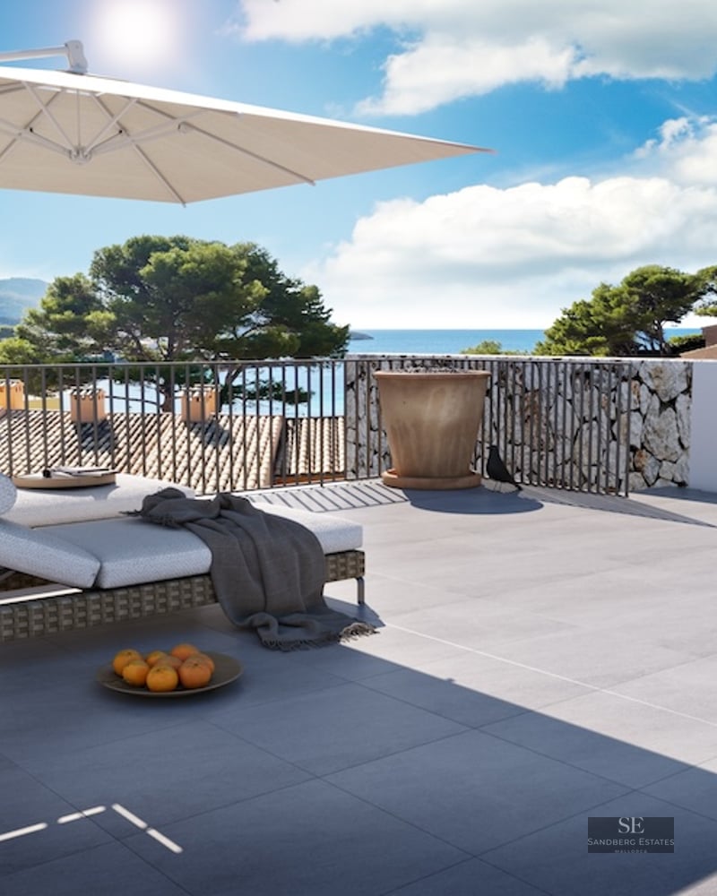 Sunny terrace with lounge chairs, large umbrella, and panoramic sea and mountain views.