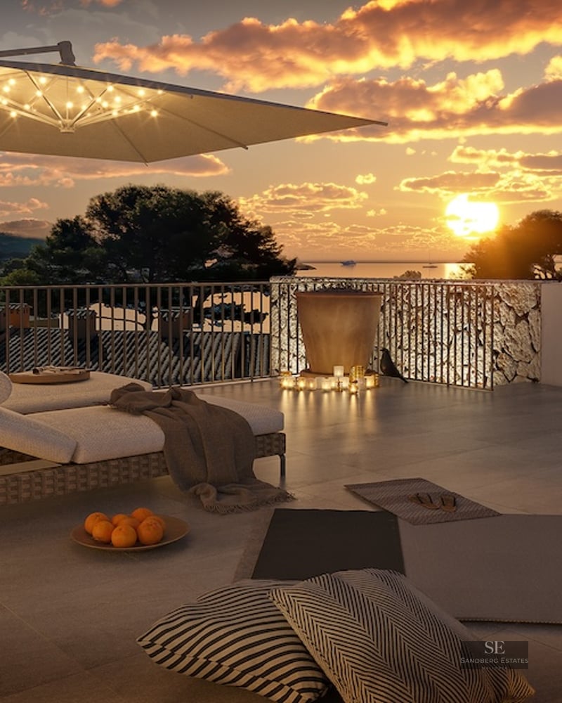 A luxury rooftop terrace at sunset featuring designer loungers, warm ambient lighting, and panoramic sea views.