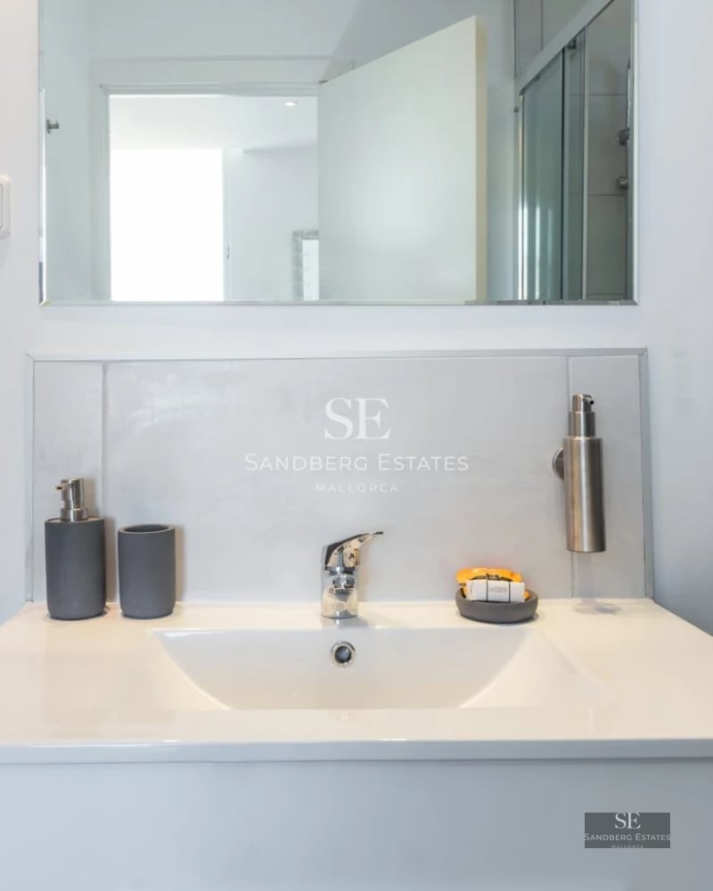 Spacious living room with floor-to-ceiling windows, wood floors, fireplace, and modern designer furniture. Pendant lights provide warm light.