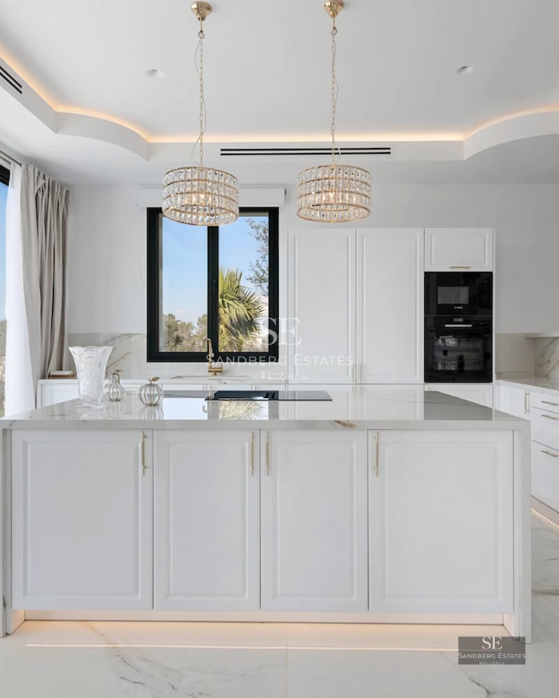 Spacious living room with pool access. Large windows, light wood floors, modern sofas, and unobstructed views. Abundant natural light.