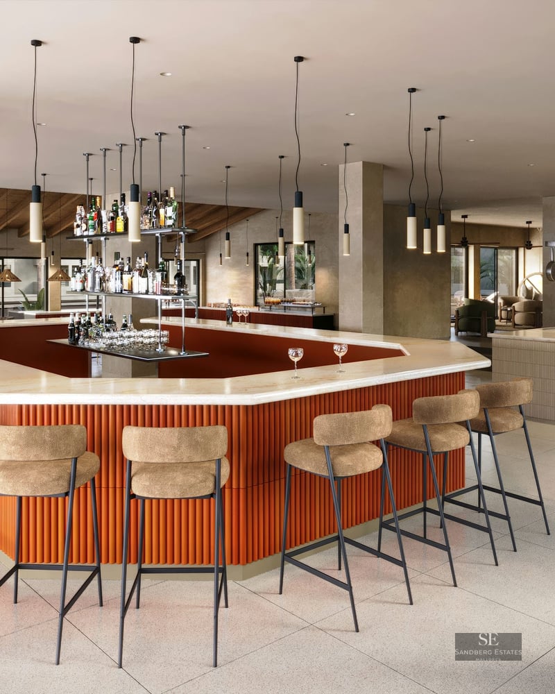 Bar moderne avec comptoir en marbre, base en terre cuite striée et tabourets hauts dans un espace social lumineux.