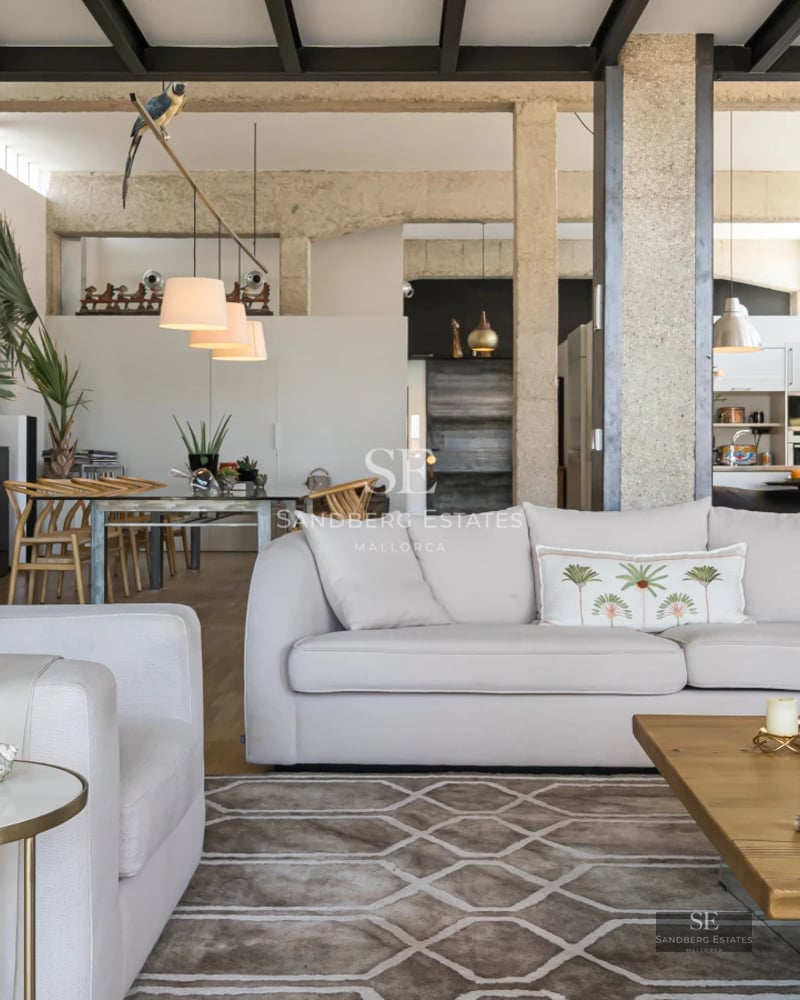 View of modern villa with infinity pool and lounge chairs. Minimalist architecture with large windows. Manicured garden and blue sky.
