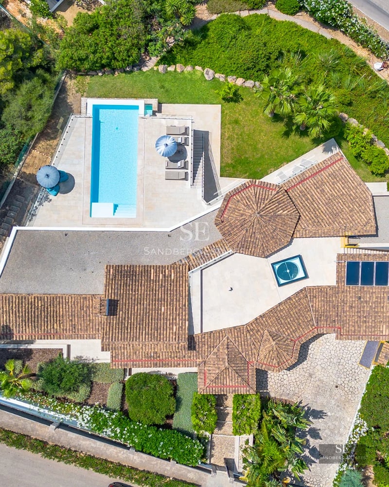 Exterior view of modern villa with infinity pool, garden, and spacious terraces. Minimalist design with large windows and elegant architecture.