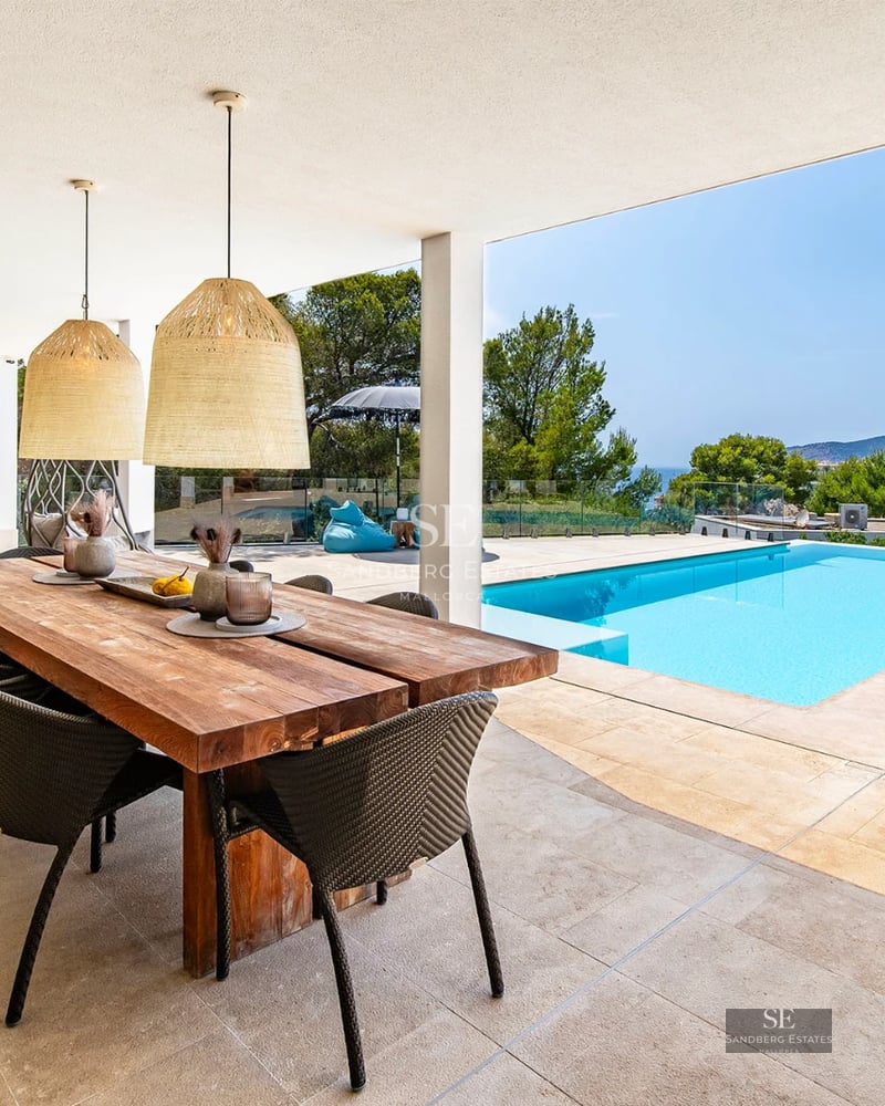 Spacious living room with picture windows, beige sofas, and a wooden coffee table. Panoramic sea views from the balcony. Modern and bright design.
