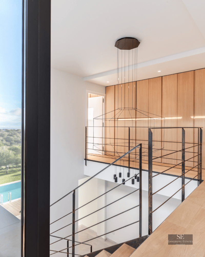 Interior view of a wooden landing with metal railings and a large window overlooking an outdoor swimming pool.