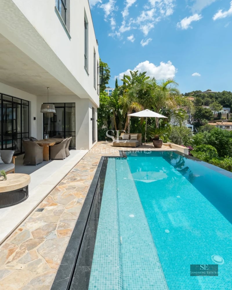 Exterior view of a modern villa featuring a pool, manicured garden, and ample outdoor living spaces.