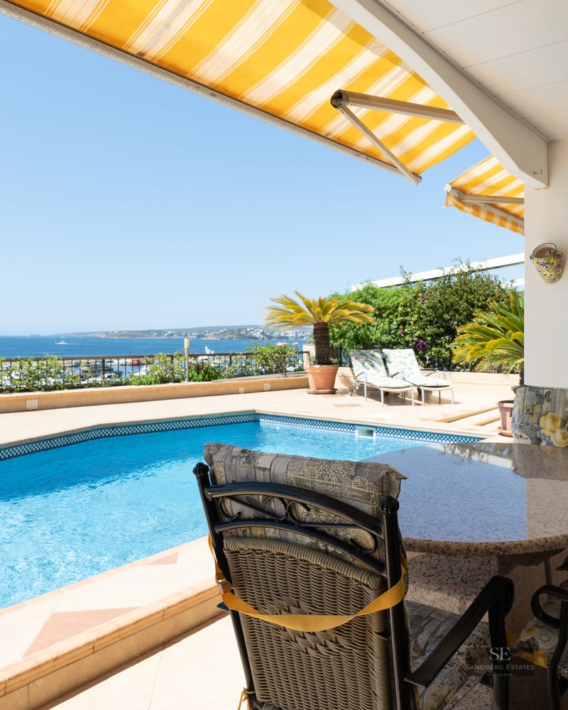 Outdoor terrace featuring a blue swimming pool, dining set, and yellow awnings with panoramic ocean views.
