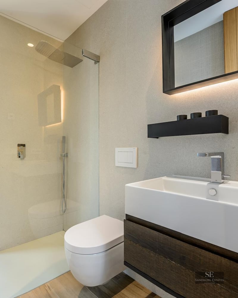 Modern bathroom featuring a white vessel sink, dark wood vanity, walk-in glass shower, and large window with green views.
