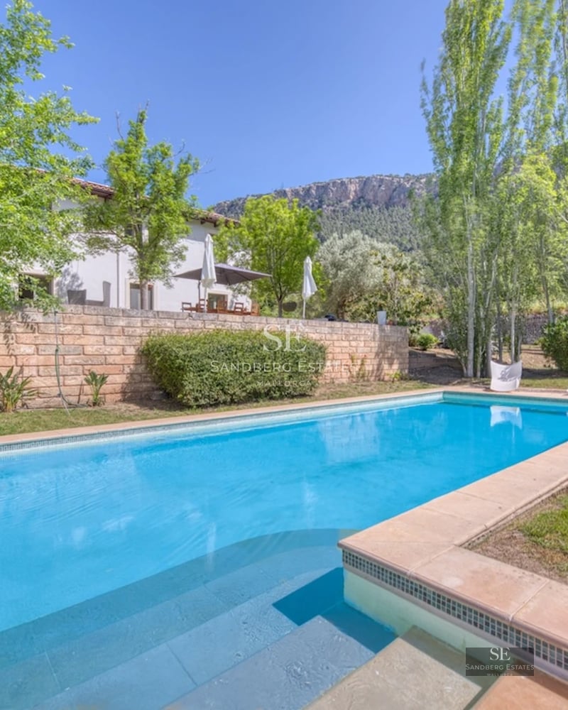 Image of a luxurious villa with a pool, surrounded by gardens and offering stunning views. Modern and elegant architecture.