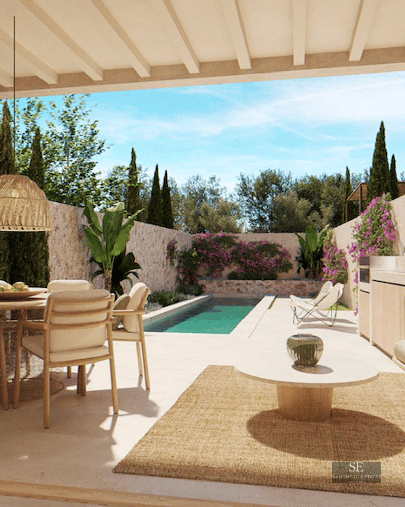 A covered terrace with a dining set, sofa, and outdoor kitchen, overlooking a long swimming pool and lush garden.