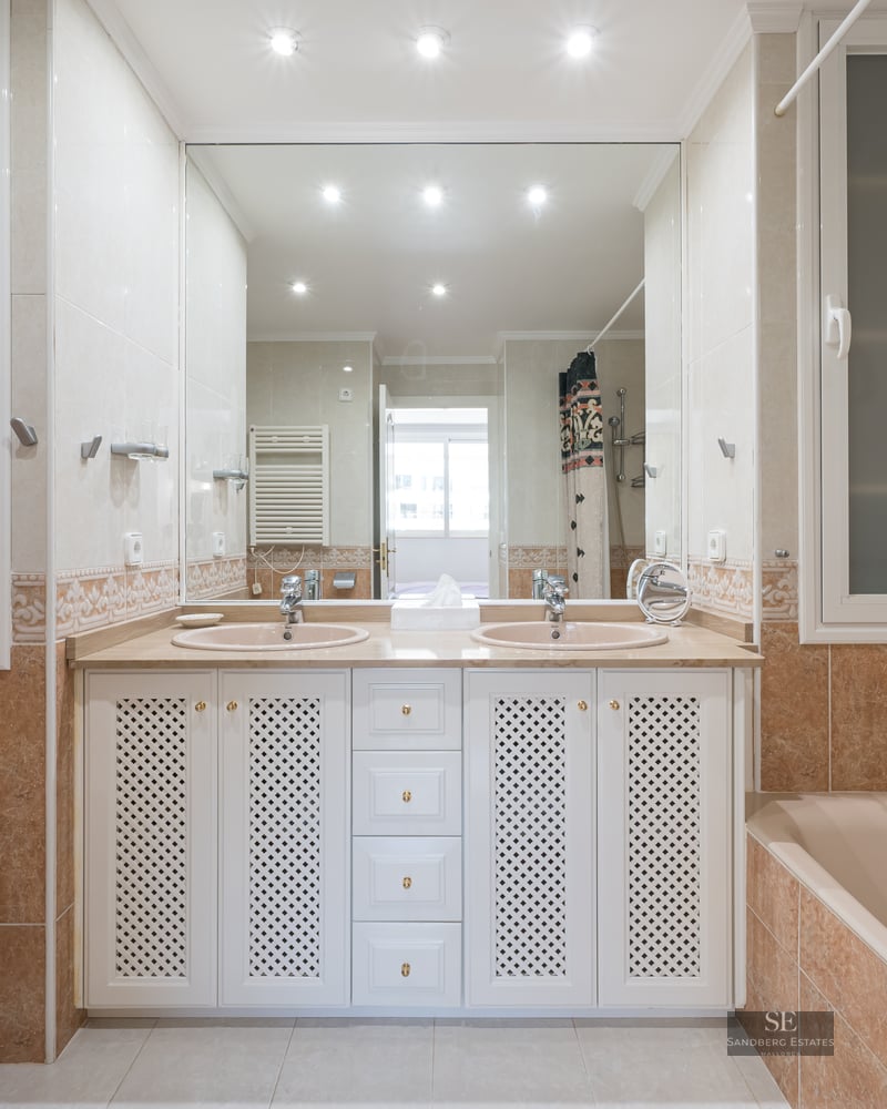 Spacious bathroom with double sinks, large mirror, bathtub, and bidet in warm beige and terracotta tones.