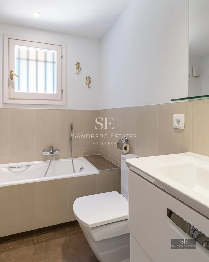 Spacious living room with large windows offering panoramic sea views. Modern, elegant design. Gray sectional sofa and light wood flooring.