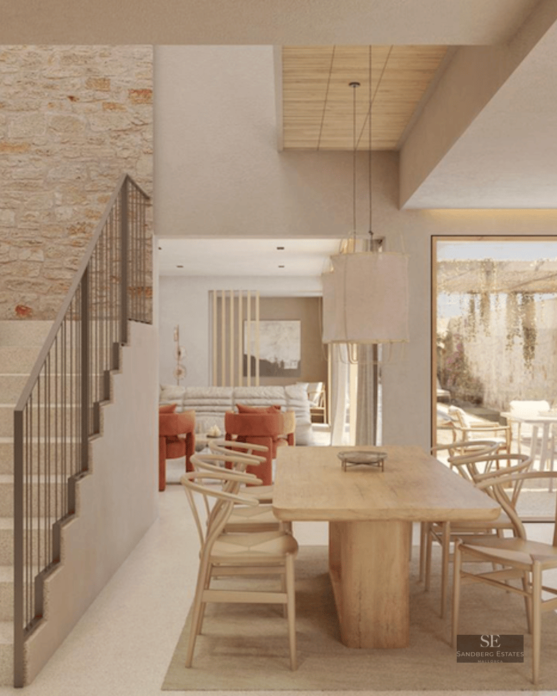 Bright modern interior featuring a large wooden dining table, stone feature wall, and an elegant stone staircase.
