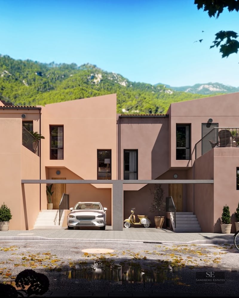 Contemporary terracotta-colored townhouses against a lush mountain backdrop with people cycling on the street.