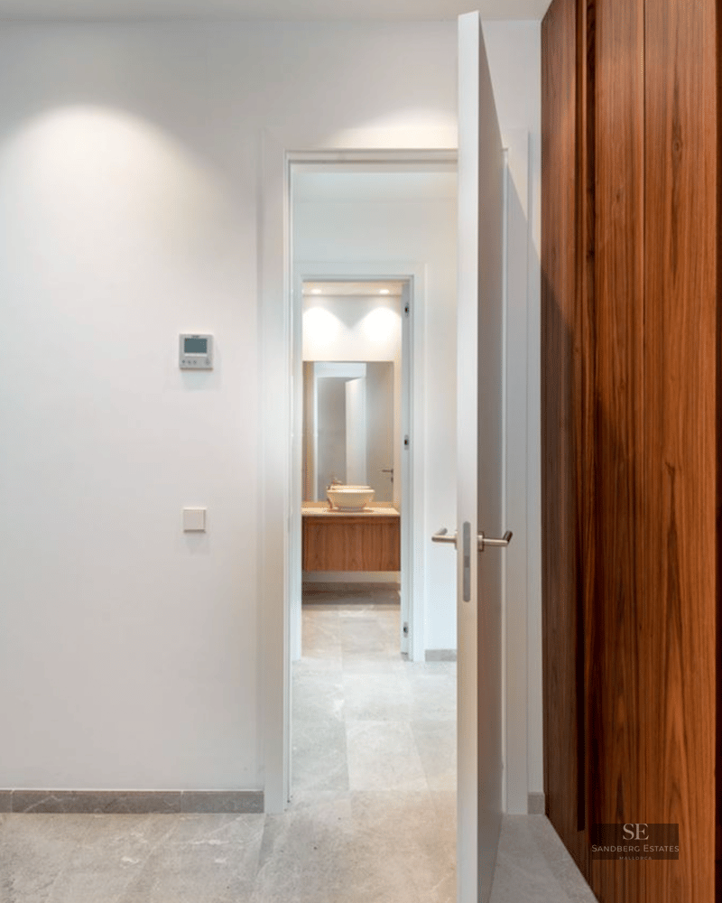 A large wooden built-in wardrobe next to an open door leading to a modern bathroom with a vessel sink.
