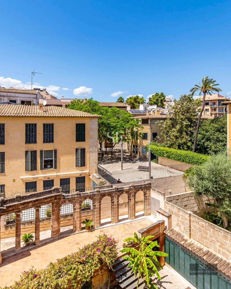 Spacious living room with window walls, leather sofas, fireplace, and built-in shelves. Natural light and garden view.