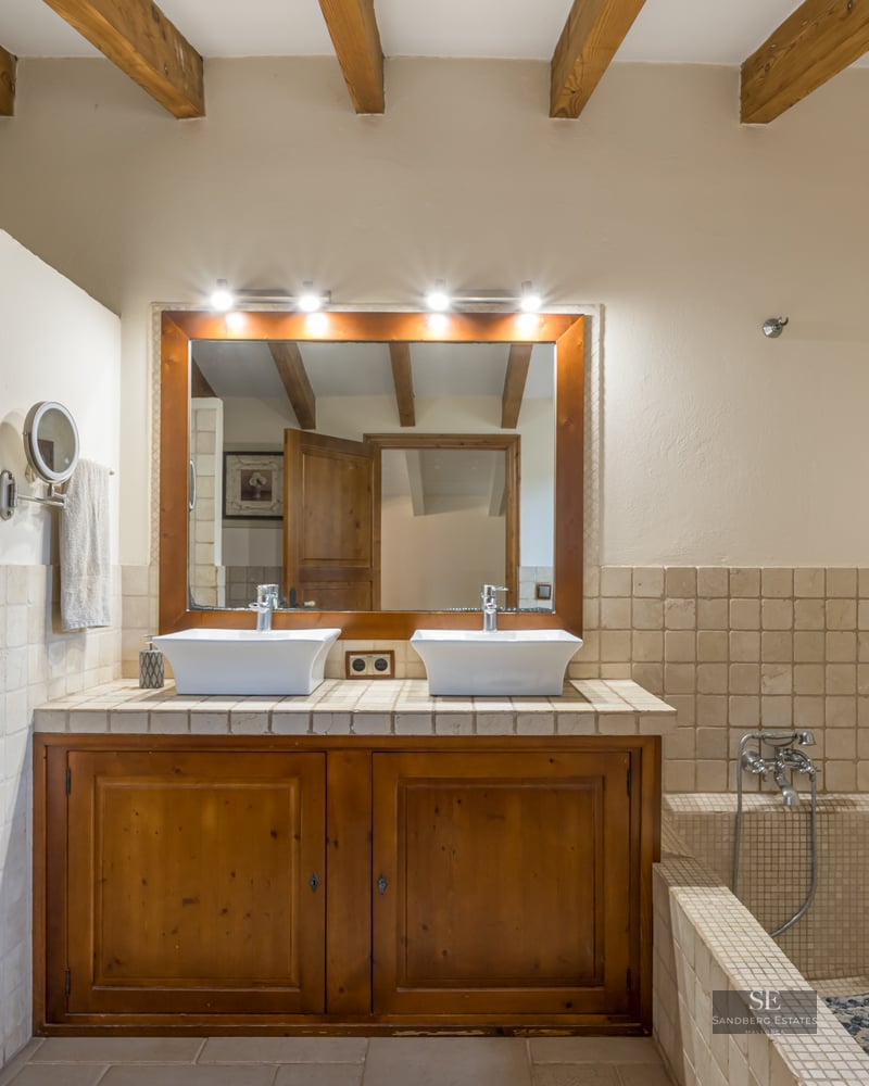 Master bathroom with double vessel sinks, wooden vanity, exposed ceiling beams, a walk-in shower, and a tiled bathtub.