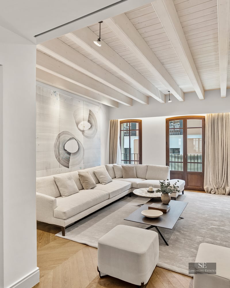 Spacious modern living room featuring a white sectional sofa, wooden ceiling beams, and a private elevator access.