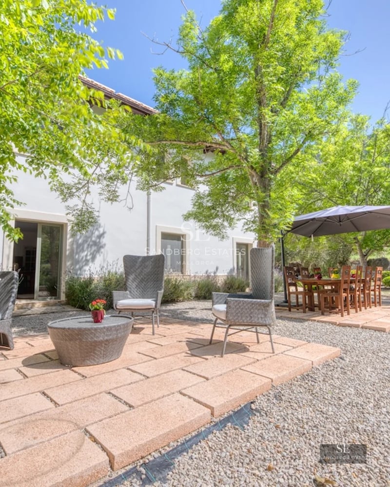 Image of a swimming pool with panoramic views, surrounded by lush greenery and a modern house with large glass windows.
