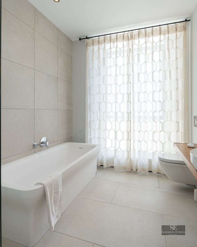 Large bathroom featuring a white bathtub, vessel sink on a wooden counter, and glass shower screen.