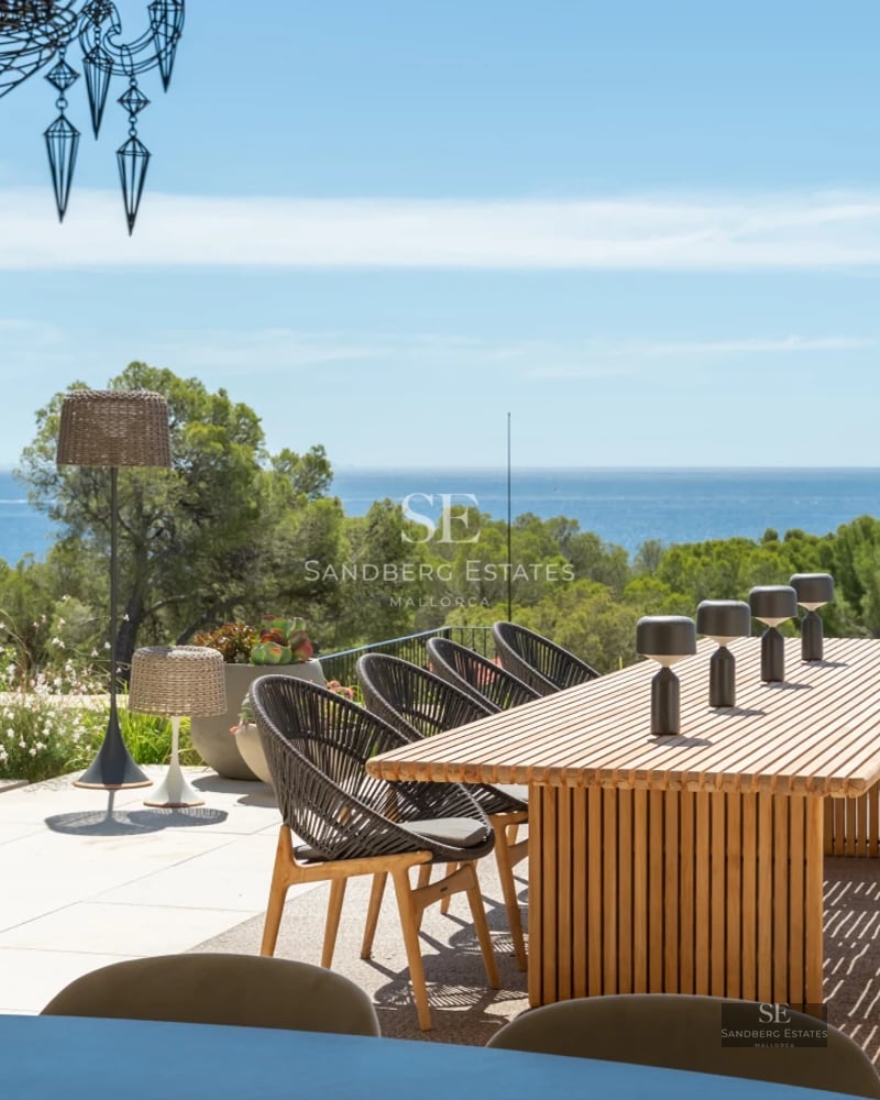 Spacious balcony featuring wooden flooring, glass railing, and panoramic sea views. Modern furniture and minimalist design.