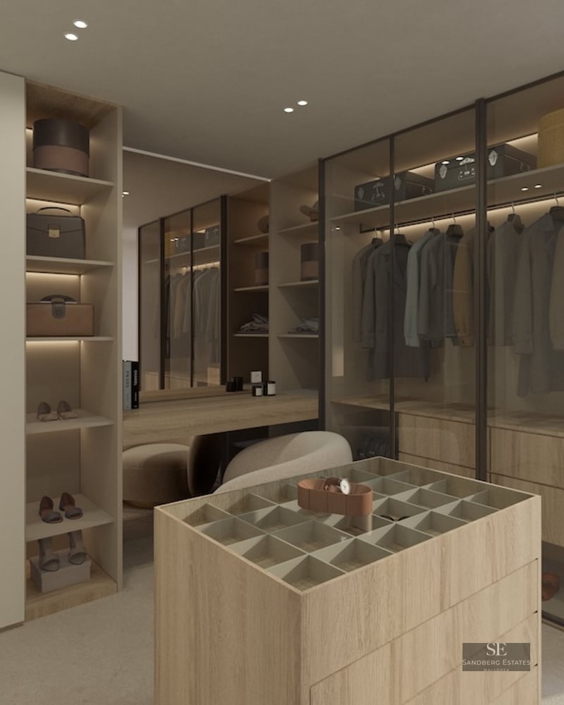 A minimalist walk-in closet featuring light wood cabinetry, glass wardrobes, a central accessory island, and natural light.