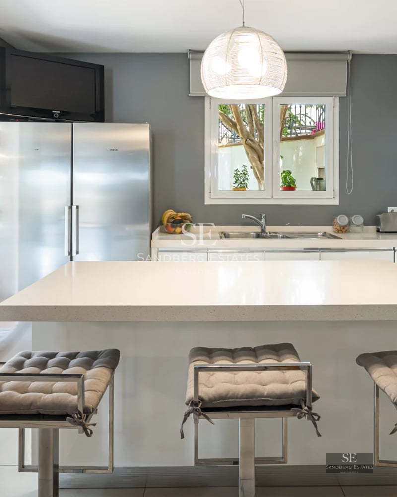 View of a modern pool surrounded by green lawn and contemporary architecture featuring large windows and clear blue sky.