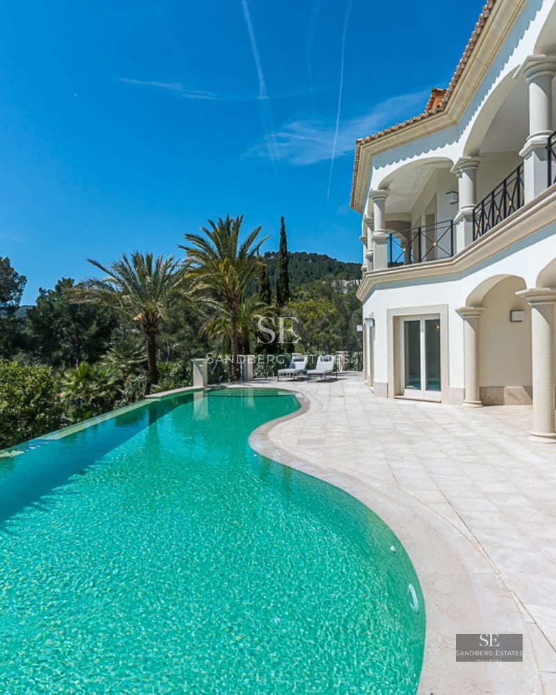Spacious living room with floor-to-ceiling windows, designer sofas, modern fireplace and panoramic views. Natural and warm lighting.