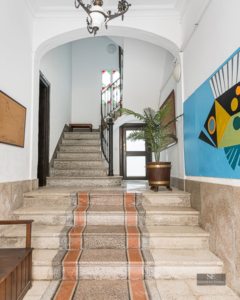 Entrance with stone stairs, wooden bench, and a large colorful fish mural on the wall.